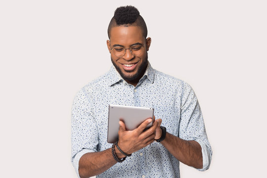 African guy using tablet standing isolated on grey background  - Powered by Adobe