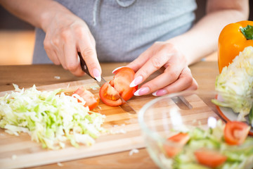cooking, food and concept of veganism, vigor and healthy eating - close up of female hand cutting vegetables for salad