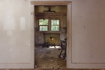 Looking through doorway into trashed kitchen in an abandoned home