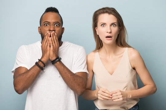 Shocked diverse young couple looking at camera.