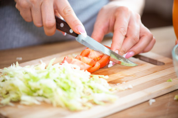 cooking, food and concept of veganism, vigor and healthy eating - close up of female hand cutting vegetables for salad