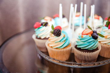 Homemade cupcakes traditional American sweet baked dessert with berries. fruit tartlets on a wooden plate on the table, fruit baked shell, tasty cupcake with berry and butter cream
