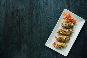Rolls with fresh chicken breast with greens, carrot slices, bell peppers on a dark cutting board. The concept of healthy homemade food. Dark wooden background.