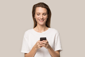 Smiling young woman using cellphone, looking at screen, chatting online