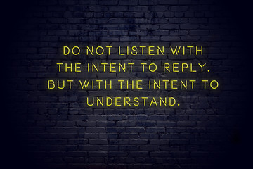 Neon sign with positive wise motivational quote against brick wall 