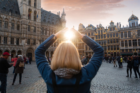 Woman stands in the square Grand Place in Brussels, Belgium at sunset.