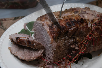 roasted lamb rolled roast on white plate on platter