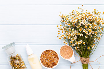 Sea salt, aromatherapy oil in bottles and chamomile on vintage wooden background.