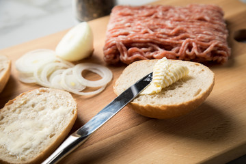 Deutsche Mettbrötchen mit rohen Schweine Mett, Brötchen, Butter, Zwiebeln, Pfeffer und Mett auf Holzbrett mit Messer in Küche