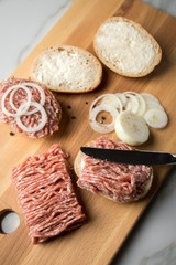 Deutsche Mettbrötchen mit rohen Schweine Mett, Brötchen, Butter, Zwiebeln, Pfeffer und Mett auf Holzbrett mit Messer in Küche