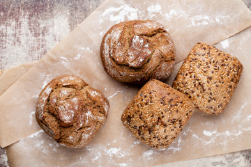 Gold rustic crusty loaves of bread and buns on wooden background. Still life captured from above top view, flat lay.