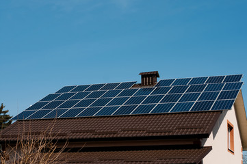 Fototapeta premium Solar panel system on house roof, sunny blue sky background.Blue solar panels.