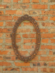 Oval bronze frame on the background of an old brick wall.