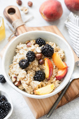 Porridge bowl oatmeal with fruits, berries, nuts and honey. Top view, vertical orientation. Concept of wellbeing, healthy eating, dieting and weight loss