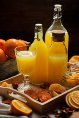 orange juice in bottles and a glass with fresh oranges, jam, on the table