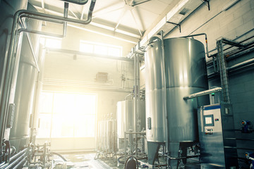 Stainless steel juice factory equipment, large reservoirs or tanks and pipes in modern plat. Industrial background