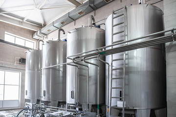 Stainless steel juice factory equipment, large reservoirs or tanks and pipes in modern plat. Industrial background