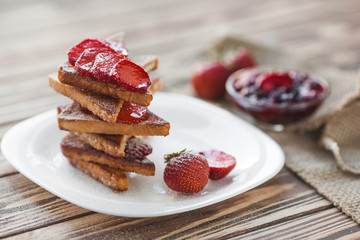 Morning breakfast. Toasts with strawberry and jam. Bread and confiture. Fresh hot toasts with cream. Delicious homemade dessert.