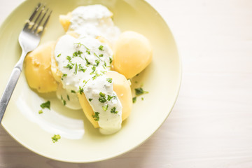 Delicious jacket potatoes. Cooked in water..Nice simple dish with sour cream. Everything on a green plate garnished with herbs.