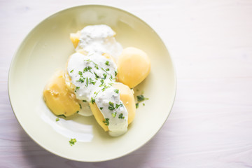 Delicious jacket potatoes. Cooked in water..Nice simple dish with sour cream. Everything on a green plate garnished with herbs.