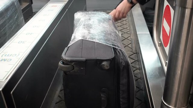 Closeup view of pasting on luggage tag, attached to red plastic suitcase at airport. Employee attaches a luggage tag to suitcase of passenger