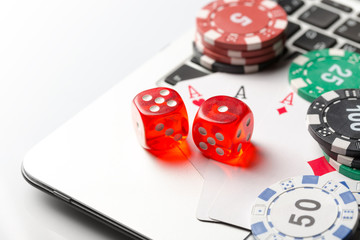 Online poker casino theme. Gambling chips with dice and playing cards on laptop.