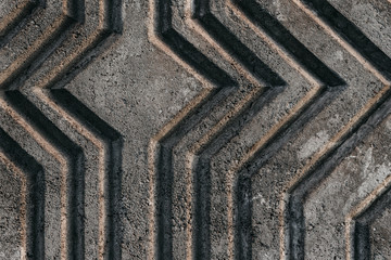 Relief gray reinforced concrete wall with curved extruded stripes with a diamond shape in the center