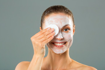 beautiful young woman with a cleansing napkin in her hand and cream mask on her face