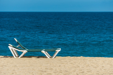 Fototapeta na wymiar Sun lounger on sandy beach with turquoise sea and blue sky