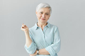 Isolated image of elegant fashionable middle aged European woman on retirement posing in studio...