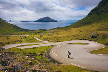Young skater riding a skateboard through beatiful scenery of Faroe Islands