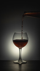 Obraz na płótnie Canvas A glass that poured alcohol on a dark background