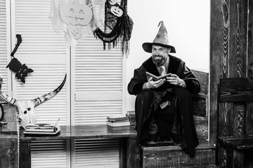 Happy Halloween story. A terrible tale at night. Good magician with a smile. Magician with a book. Reading at night. Halloween party background.