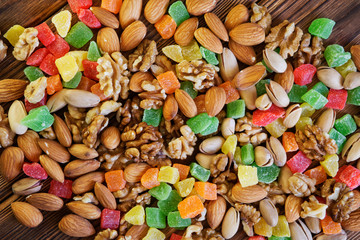 Candied fruits, pistachios, almonds and walnuts lie on a rustic wooden table made of pine planks. Autumn farm harvest