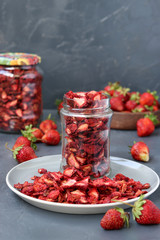 Strawberry chips are in a glass jar on a dark background, healthy food