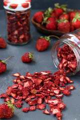 Strawberry chips are in a glass jar on a dark background, healthy food