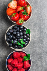 Fresh summer berries in the bowls. Blueberries, strawberries, raspberries shoot from the top