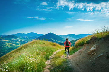 Fototapeta na wymiar Mountain biker riding through mountains and low hills area landscape