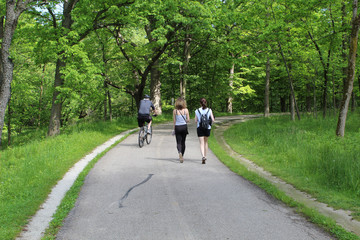 Older man an a bike passing two women on the North Branch Trail in Morton Grove, Illinois