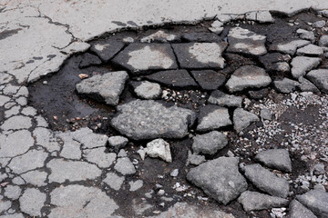 Broken pit with pieces of asphalt. Bad asphalt road. Destruction of roads, pits on the road