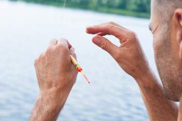 Man unraveling to the tangled and knotted Fishing line. Problem solving.