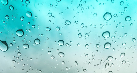 Water drops of rain on window with turquoise gradient