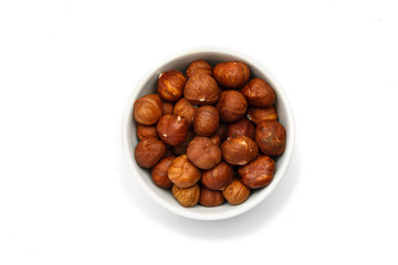 Hazelnut in ceramic bowl on white background, top view