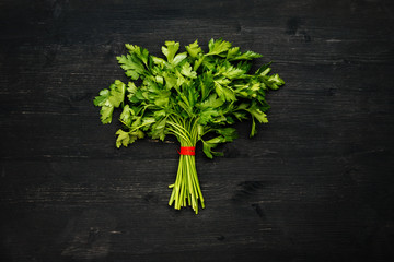 Bunch of green fresh parsley on a black wooden table, top view
