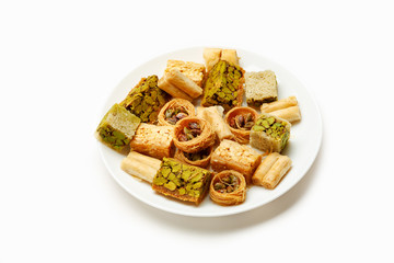 Traditional oriental sweets in white plate with different nuts on a white table, side view