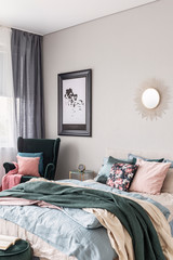 Sun shape like mirror and map in black frame on grey wall of fashionable bedroom interior with king size bed with cozy bedding