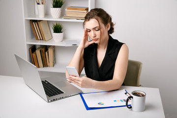 Confused and serious office woman working phone sitting at her desk