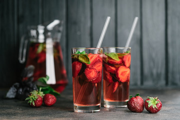 Fresh summer strawberry lemonade with basil and ice on a dark background.