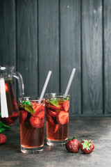 Fresh summer strawberry lemonade with basil and ice on a dark background copy space.