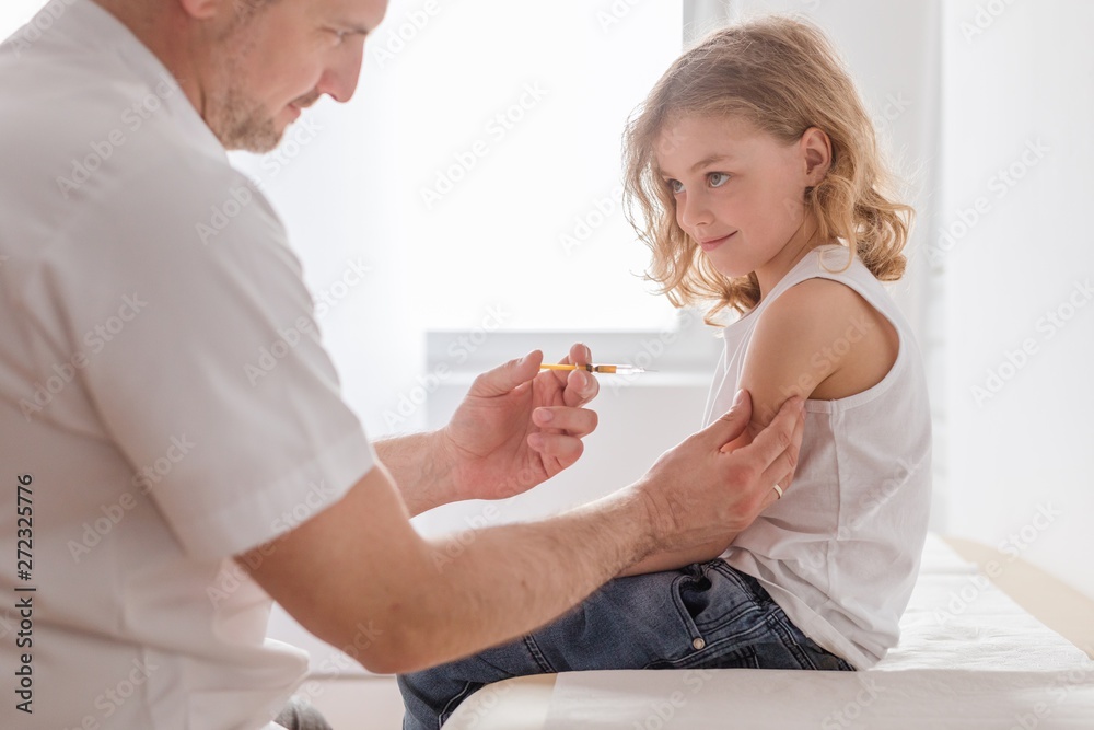 Wall mural Close-up of a sweet blond boy and a doctor with a syringe